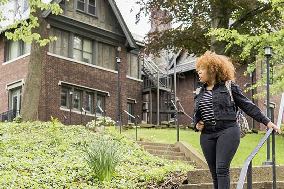 Photo of a Chatham University student standing at the top of outdoor stairs on Shadyside Campus, looking away from the camera